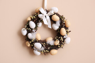Beautiful Easter wreath decorated with eggs on beige wall