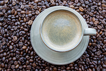 Cup with coffe on the roasted coffe beans.