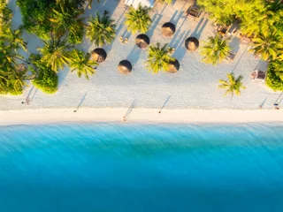 Foto auf Leinwand Aerial view of green palm trees, umbrellas on the sandy beach of Indian Ocean at sunset. Summer holiday in Kendwa, Zanzibar island. Tropical landscape with palms, white sand, clear blue sea. Top view © den-belitsky