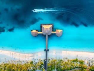 Foto auf Acrylglas Aerial view of bungalow, boat in Indian Ocean at sunset in summer. Restaurant on the sea. Top drone view of wooden hotel, azure water, white sandy beach, palm trees. Luxury resort in Kendwa, Zanzibar © den-belitsky
