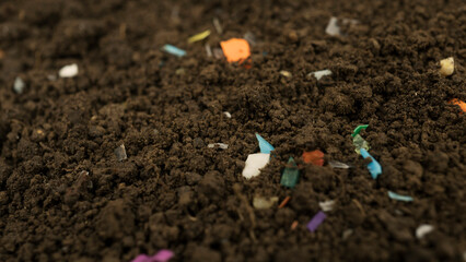 Microplastics inside the soil. Concept of plastic pollution, fertilizing and agro industry. Non-recyclable plastic pollution in the compost at the field. Selective focus.