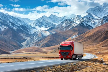 Red semi truck driving on scenic asphalt road through breathtaking snow-capped mountain landscape