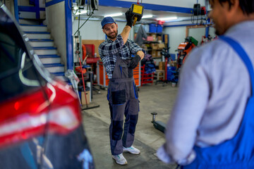A skilled mechanic takes control, managing the workshop's car lift with precision.