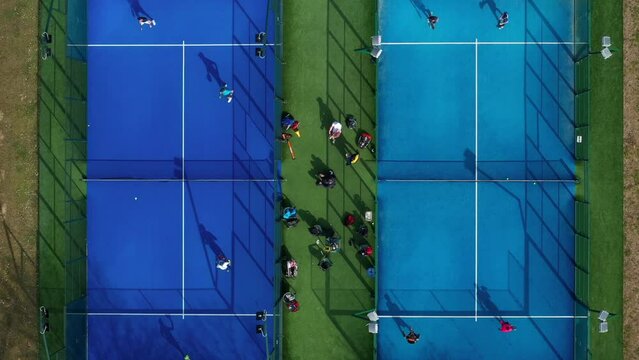 Aerial view of unrecognizable tennis athletes seen from above playing a game of paddle tennis at an outdoor paddle tennis court 