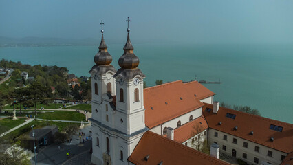 Tihanyi Bencés Apátság, or the Benedictine Abbey of Tihany, is a historic monastery located in Tihany, Hungary, perched on a scenic hill overlooking Lake Balaton captured from a drone - obrazy, fototapety, plakaty