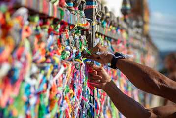 A Catholic faithful is seen tying a souvenir ribbon on the railing of the Senhor do Bonfim church...