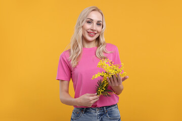 Happy young woman with beautiful bouquet on orange background