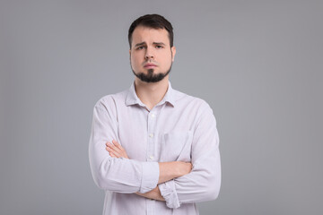 Portrait of sad man with crossed arms on grey background