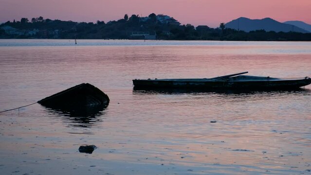 Silhouette of boats on nightfall sea surface. A view of surfing boats silhouette in the river water during colorful sunset in summer.