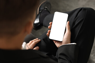 Naklejka premium Man using smartphone with blank screen indoors, closeup. Mockup for design