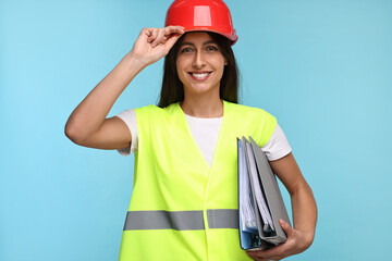Architect in hard hat with folders on light blue background