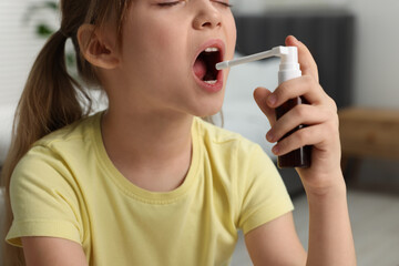 Little girl using throat spray at home, closeup