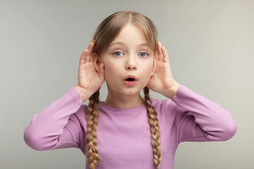 Little girl with hearing problem on grey background