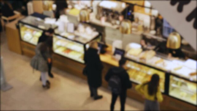 A blurred image of shoppers browsing and buying products in a crowded store.