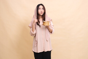 beautiful asian woman kissing forward looking up while pointing up and holding a wooden bowl in front of her chest containing delicious dimsum