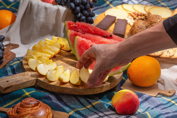 Close-up view of cut fruits against the background of laid out picnic food, selective focus. The...