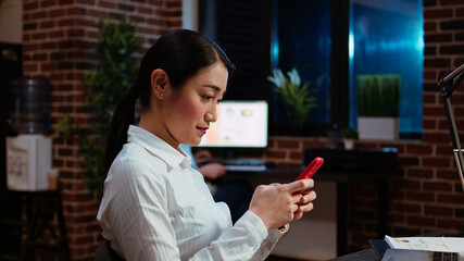 Financial analyst looking at text messages on smartphone, taking break from work with business...