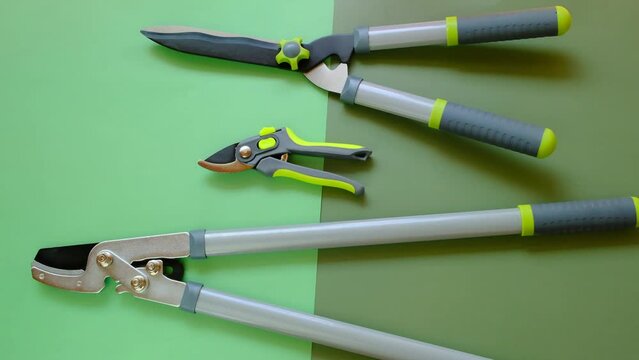 Plants Pruning Tool. Secateurs, loppers and hedge trimmers on a green combined background.Garden equipment and tools. Tools for pruning and trimming plants. 4k footage