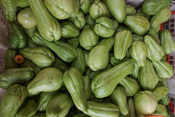 Pile green chayote vegetables on a basket, at a traditional market, stock photo.