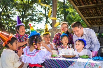 The little Latin boy blows out the candles and thus celebrates his birthday surrounded by his family and friends.