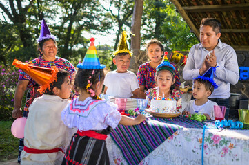 Latin girl blows out the candles at her birthday celebration, her friends and family accompany her...