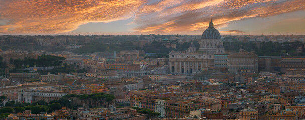 An aerial view of Rome at dusk highlights St. Peter's Basilica and warm hued buildings. The sky, with orange, pink, and purple, underscores Rome's architectural richness and urban density.