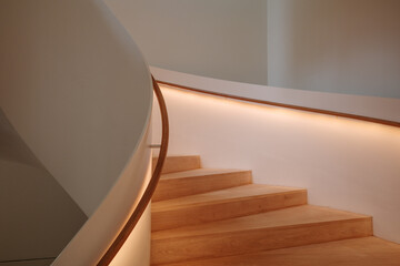 Interior staircase featuring a smooth curve, with warm light emanating from the built-in...
