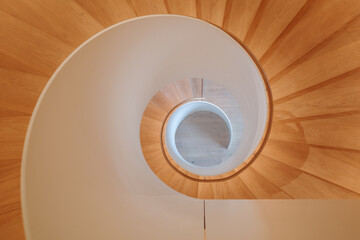 An overhead view of a contemporary spiral staircase with a flawless white balustrade and warm...