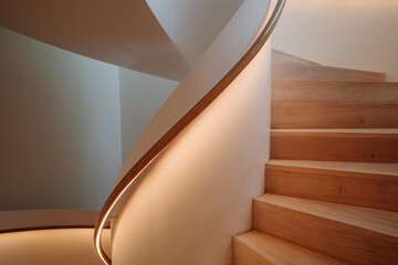 Interior staircase featuring a smooth curve, with warm light emanating from the built-in...