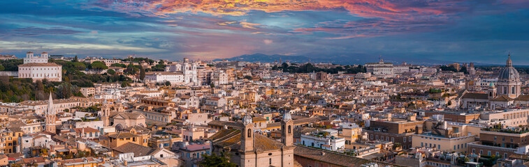 Fototapeta na wymiar An aerial view of Rome at dusk reveals terracotta rooftops, church domes, and spires against a sunset. White buildings and mountains highlight the city's ancient modern mix.