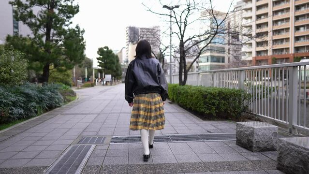 A Japanese woman in her 20s walking on the road around Gotanda Station, Shinagawa-ku, Tokyo in winter 冬の東京都品川区五反田の駅周辺の道を歩く２０代の日本人女性 