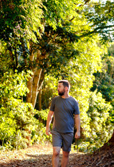 A man walks along a park trail, surrounded by sun-kissed trees, evoking feelings of tranquility and exploration.