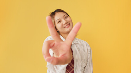Smiling young woman dressed in shirt and tie showing fingers sign of victory and freedom gesture at...
