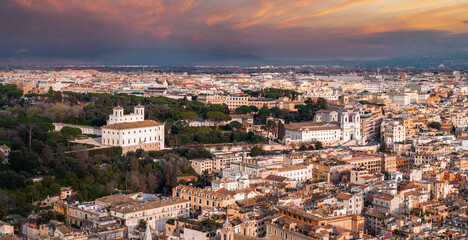 An aerial view of Rome at sunrise or sunset highlights its mix of old and modern buildings under a...
