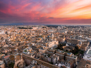 An aerial view of Rome at dusk reveals a sky changing from pink to blue, with the city in golden...