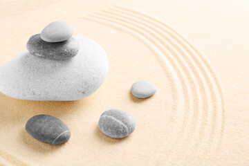 Fototapeta na wymiar Zen garden stones on sand with pattern. Space for text