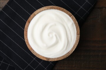 Delicious natural yogurt in bowl on wooden table, top view