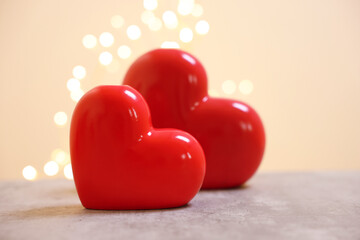 Ceramic hearts on grey table against blurred lights