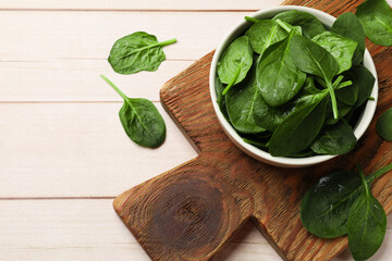 Fresh spinach leaves on light wooden table, top view. Space for text