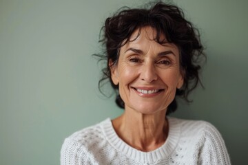 Portrait of a smiling senior woman looking at camera against grey background