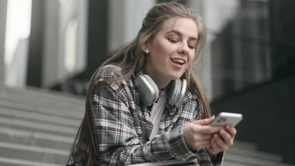 Tired exhausted boring young woman freelancer student with smartphone dozing while remembered about incredible news promotion sale interesting education app or website near university outdoors