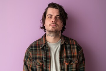 Portrait of a handsome young man with tattoos on his arms. Isolated on purple background.