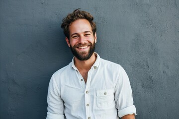 Portrait of a handsome young man standing against grey background and smiling - obrazy, fototapety, plakaty