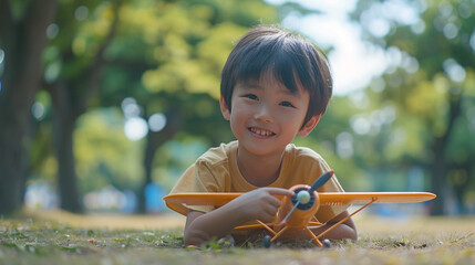  A boy in a park, having fun with a model airplane, his excitement obvious as he stares into the camera. - obrazy, fototapety, plakaty