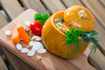 Dietary squash soup in baked pumpkin bowl. Recipe: flesh of whole baked pumpkin pull out with spoon, puree in blender, add olive oil, salt, pepper. Pour in pumpkin. Serve with greens and pumpkin seeds