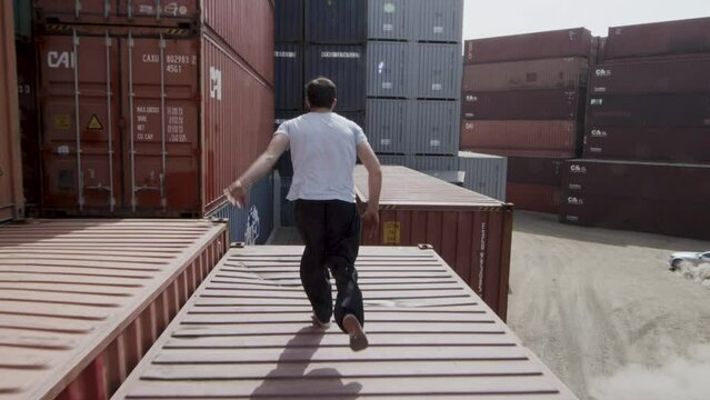 Stunt man jumping across shipping containers - steady cam shot
