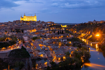 Cityscape of Toledo in evening illuminated by city lights. Province of Toledo, Castilla-La Mancha, Spain. - obrazy, fototapety, plakaty
