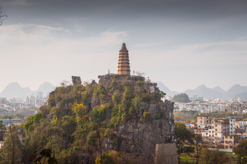 Ancient pagoda on the hill surrounded by limestone mountains and city buildings
