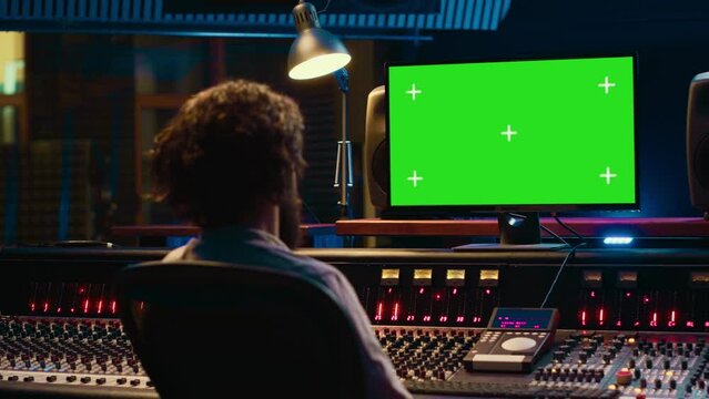Tracking engineer watching tutorials online to learn mixing and mastering techniques, greenscreen display on pc and processing sounds. Artist technician operates control room switchers. Camera A.