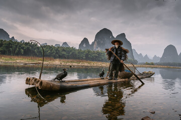 Cormorant fisherman and his birds on the Li River in Yangshuo, Guangxi, China.